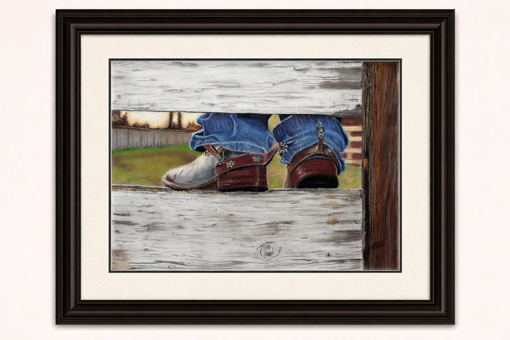 Framed  coloured pencil artwork of cowboy boots on a wooden fence.